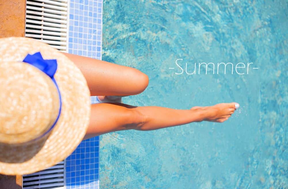 A young woman relaxing on a pool side lounge under a hat